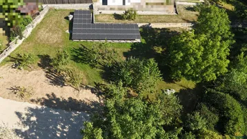Luftaufnahme eines Grundstücks mit Solaranlage und Baumbestand in ländlicher Umgebung.