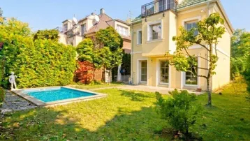Gelbes Einfamilienhaus mit Garten, kleinem Pool und Balkon in sonniger Umgebung.