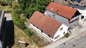 Luftaufnahme zweier Wohnhäuser mit roten Ziegeldächern und umgebender Grünfläche.