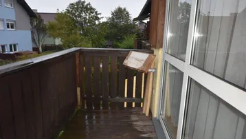 Kleiner Holzbalkon mit Blick auf die Nachbarschaft an einem regnerischen Tag.