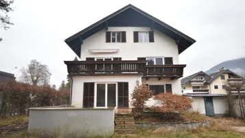 Traditionelles Haus mit Satteldach, mehreren Balkonen und Gartenbereich.