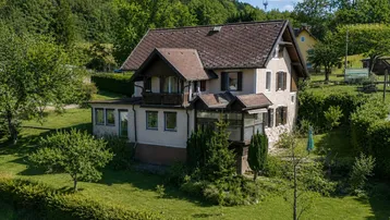 Charmantes Einfamilienhaus mit Satteldach, umgeben von üppigem Grün und Bäumen in ländlicher Umgebung.
