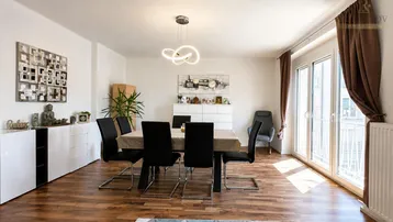 Heller Wohn- und Essbereich mit modernem Holzboden, stilvoller Einrichtung und Zugang zum Balkon.