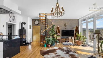 Geräumiges Wohnzimmer mit Holzboden, Kamin, Wendeltreppe und Zugang zur Terrasse mit Weitblick.
