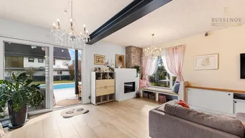 Lichtdurchfluteter Wohnbereich mit Zugang zum Außenbereich und Pool, ausgestattet mit modernem Kamin.