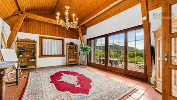 Helles Wohnzimmer mit Holzbalkendecke, Terrakottaboden und weitem Blick ins Grüne.