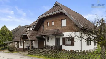 Ansicht des Hauses von vorne mit traditioneller Holzverkleidung und Satteldach.