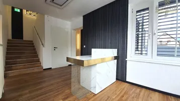 Moderner Eingangsbereich mit Rezeptionstresen, Holzfußboden und Treppenaufgang, ideal für eine Praxis oder Büro.