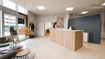 Heller Empfangsbereich mit moderner Holztheke, großen Fenstern und bequemen Sitzgelegenheiten für Besucher.