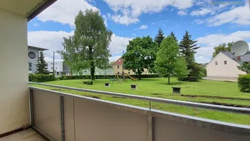 Balkon mit Blick auf eine grüne Wiese und einen kleinen Spielplatz.