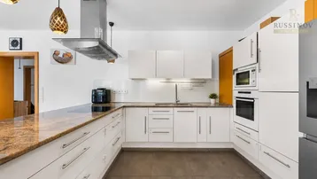 Moderne Küche mit weißen Schränken, Granitarbeitsplatte und integrierten Geräten, ideal für kulinarische Aktivitäten.