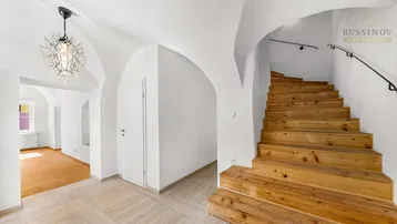 Heller Eingangsbereich mit gewölbten Decken, Holztreppe und modernen Fliesenboden.