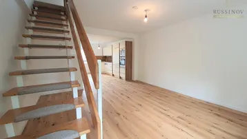 Offener Wohnbereich mit Holzboden und Blick auf die moderne Küche im Hintergrund.