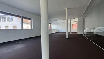 Großes, offenes Büro mit Teppichboden, vielen Fenstern und modernen Glaswänden für flexible Raumgestaltung.