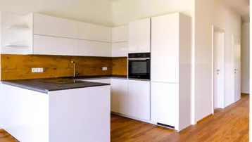 Moderne, helle Küche mit weißen Hochglanzfronten, Holzakzenten und integrierten Geräten.