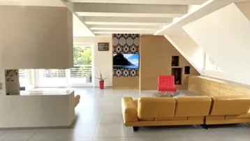 Geräumiges Wohnzimmer mit gelbem Sofa, Kamin und modernem TV-Bereich unter Dachschrägen.