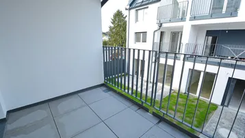 Geräumiger Balkon mit Fliesenboden und Blick auf den Innenhof und umliegende Gebäude.