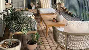 Geräumiger Balkon mit Holzboden, bequemen Sitzmöbeln und Pflanzen, ideal zum Entspannen im Freien.
