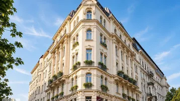 Eindrucksvolle Eckfassade eines historischen Gebäudes mit zahlreichen Fenstern und dekorativen Balkonen unter blauem Himmel.