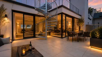 Große Dachterrasse mit gemütlichen Sitzbereichen, Esstisch und Wendeltreppe bei Sonnenuntergang.