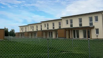 Reihenhäuser in moderner Architektur mit hellen Fassaden und großzügigen Fenstern, umgeben von Grünflächen.