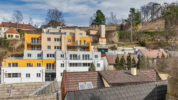 Panoramablick auf moderne Wohngebäude mit farbigen Fassaden und die umliegende hügelige Landschaft.