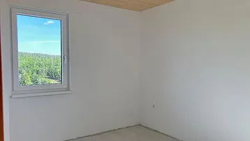 Heller Raum mit Fenster und weitem Blick auf die bewaldete Landschaft.