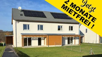 Modernes Reihenhaus mit Photovoltaikanlage auf dem Dach und grünem Gartenbereich, beworben mit zwei mietfreien Monaten.