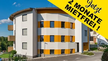 Modernes Mehrfamilienhaus mit markanter weiß-oranger Fassade, Balkonen und Außenparkplätzen in grüner Umgebung.