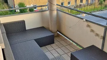 Gemütlicher Balkon mit Rattanmöbeln und Blick auf die Umgebung.