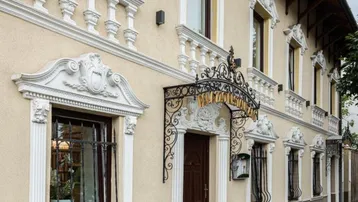 Elegante Fassade eines Gebäudes mit aufwendigen Stuckverzierungen und schmiedeeisernen Details am Eingang.
