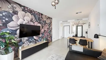 Modernes Wohn- und Esszimmer mit auffälliger Blumentapete und stilvoller Beleuchtung.