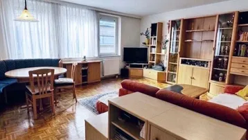 Geräumiger Wohn-Essbereich mit Fischgrätparkett, gemütlicher Sitzecke und Essbereich am Fenster.
