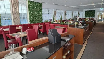 Geräumiger Restaurantbereich mit roten Sitzbänken, Holzelementen und dekorativen Pflanzenwänden.