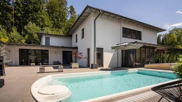 Großzügiger Außenbereich mit modernem Pool und Sonnenterrasse vor dem Haus.