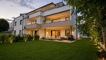 Moderne Wohnanlage mit gepflegtem Garten, großer Terrasse und Balkonen, ideal für entspannte Abende im Freien.