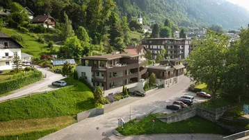 Moderne Wohnanlage in Hanglage mit mehreren Balkonen und Blick auf die umliegende Berglandschaft.