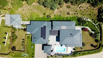 Luftaufnahme des Anwesens mit weitläufigem Garten, Pool und Photovoltaikanlage auf dem Dach.