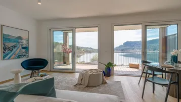 Heller Wohn- und Essbereich mit Seeblick, großen Schiebetüren und Zugang zur Terrasse.