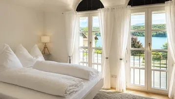 Schlafzimmer mit Seeblick, hohen Gewölbedecken und französischen Balkonen.