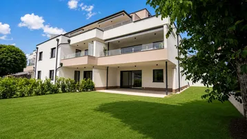 Modernes Mehrfamilienhaus mit weißer Fassade, Balkonen und großem Rasenbereich.