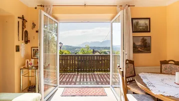Helles Wohn- und Esszimmer mit Zugang zum Balkon und weitem Blick auf die umliegende Berglandschaft.