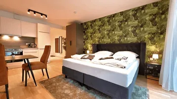 Modernes Schlafzimmer mit Doppelbett, auffälliger Tapete und integrierter Küchenzeile.