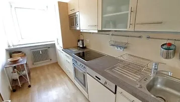Funktionale Einbauküche mit hellen Schränken, Induktionskochfeld und Fenster für Tageslicht.