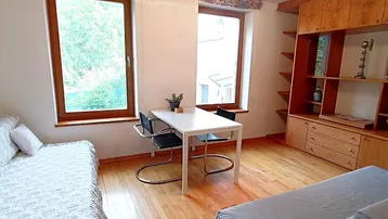 Helles Wohn- und Esszimmer mit Holzboden, Esstisch und großem Holzschrank.