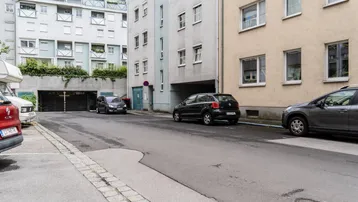 Blick auf die Straße mit parkenden Autos und der Einfahrt zur Tiefgarage.