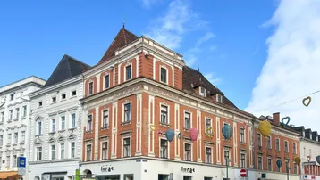 Historisches Gebäude mit roter Backsteinfassade und weißen Verzierungen an einer belebten Straßenecke.