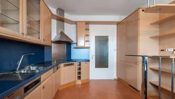 Funktionale Einbauküche mit hellen Holzfronten, blauer Arbeitsplatte und integrierten Geräten.