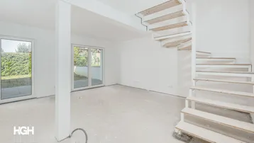 Heller, unfertiger Wohnbereich mit Rohbau-Treppe und Zugang zum Garten.