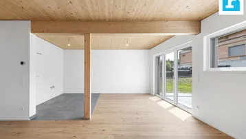Heller, offener Wohnbereich mit Holzbalkendecke, Parkettboden und Zugang zum Garten.